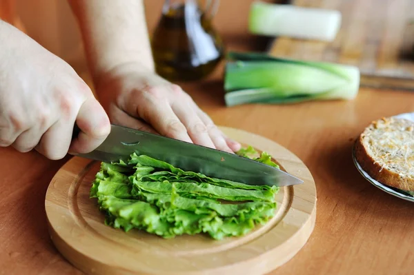 Mãos cortando salada verde — Fotografia de Stock