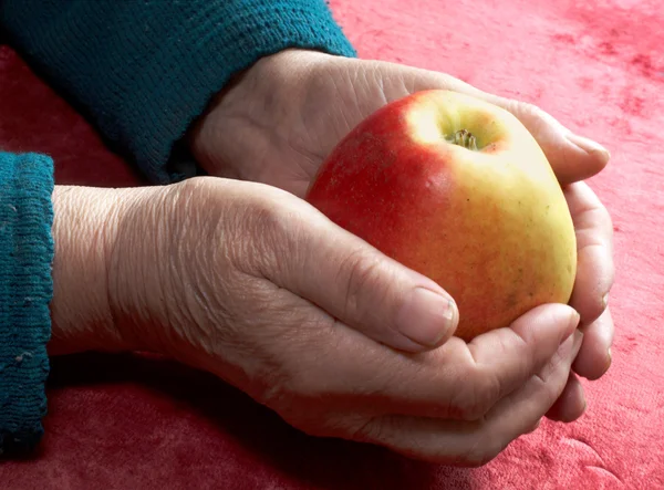 Old hands with an apple — Stock Photo, Image