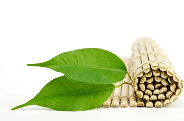 Green leaves and a bamboo mat — Stock Photo, Image