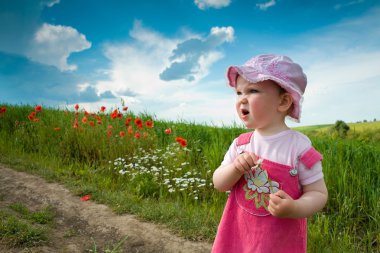 Baby-girl on a lane amongst a field clipart