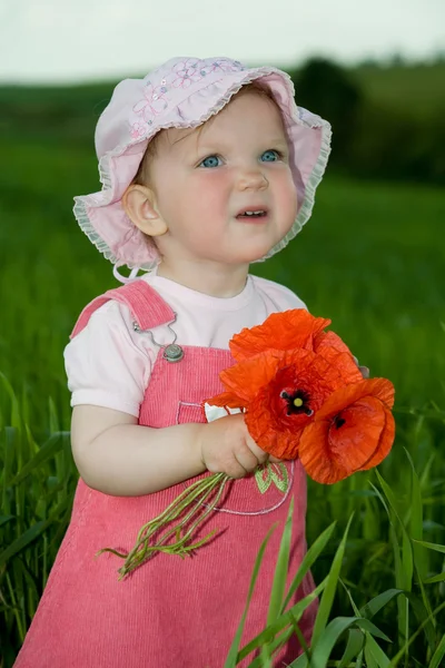 Dítě s červeným květem mezi zelené trávy — Stock fotografie