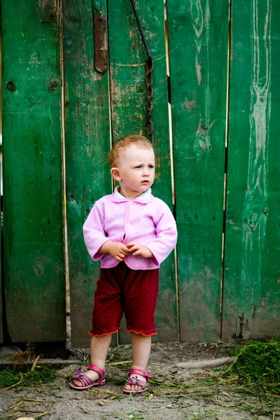 Baby-girl near green fence — Stock Photo, Image
