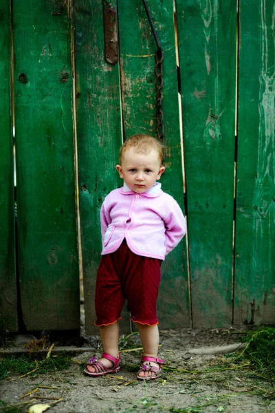 Bebê-menina perto de cerca verde — Fotografia de Stock