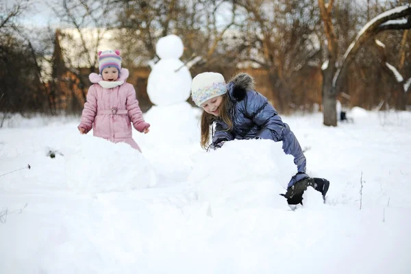 stock image Two sisters rolling snow to make snowman