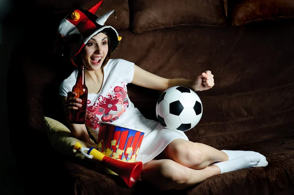 Tyttö sohvalla katsomassa jalkapalloa televisiosta — kuvapankkivalokuva