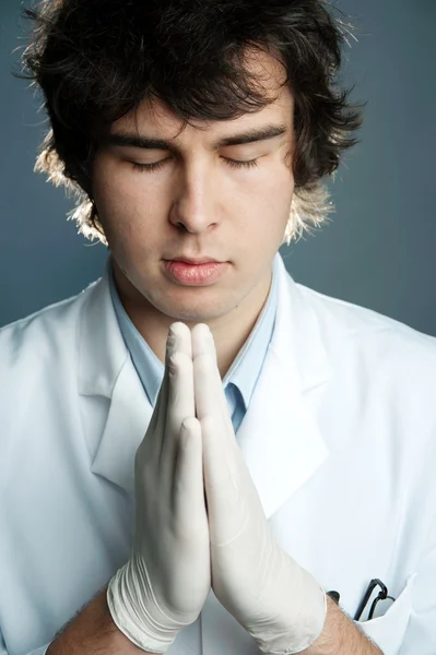 Mladý lékař v rukavicích se modlí — Stock fotografie