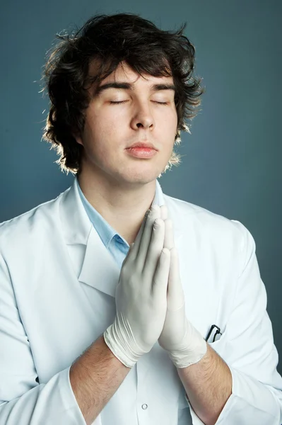 Ein junger Arzt in Handschuhen betet — Stockfoto