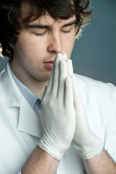 Un joven médico con guantes rezando — Foto de Stock
