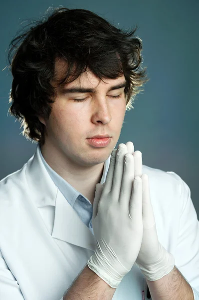 Un jeune médecin en gants priant — Photo