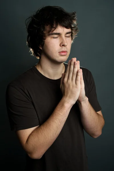 En ung man ber ensam — Stockfoto