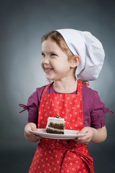 Ένα κορίτσι σε ένα λευκό καπέλο με μια τούρτα σε ένα πιάτο — Φωτογραφία Αρχείου