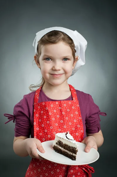 Une fille dans un chapeau blanc avec un gâteau sur une assiette — Photo