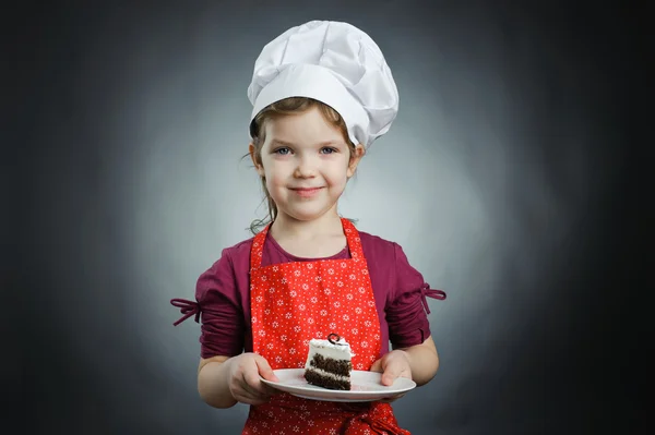 En flicka i en vit hatt med en kaka på en plåt — Stockfoto