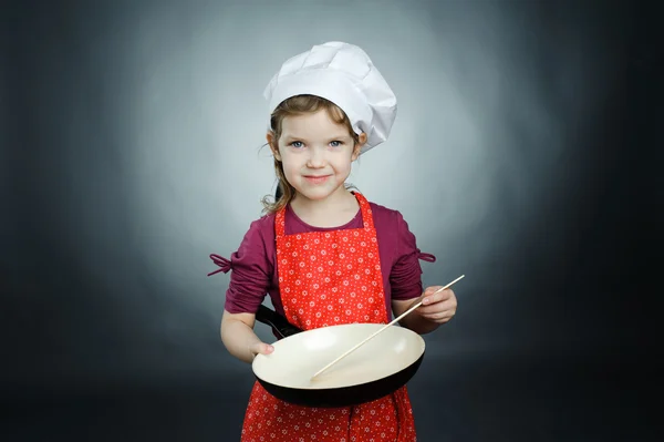 En liten flicka i vit hatt med stekpanna — Stockfoto