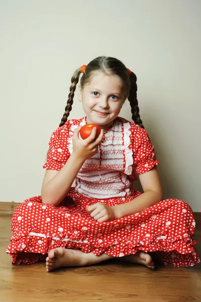 Nice little girl with a tomato — Stock Photo, Image
