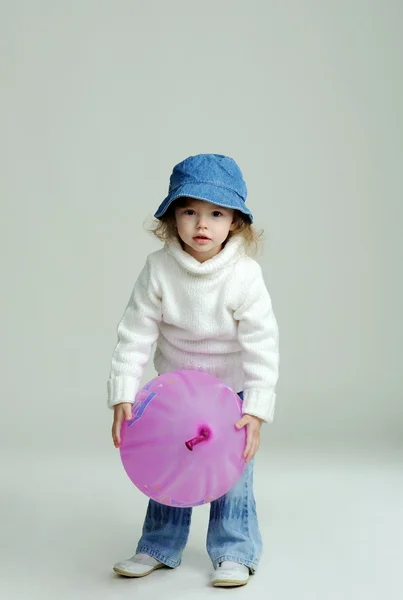 Een klein meisje in een hoed en witte trui met ballon — Stockfoto