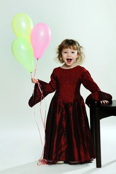 A little girl in red dress with balloons — Stock Photo, Image