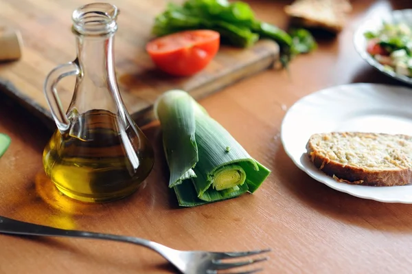 Бутылка оливкового масла и овощей на столе — стоковое фото