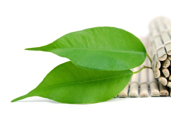 Grüne Blätter und eine Bambusmatte — Stockfoto