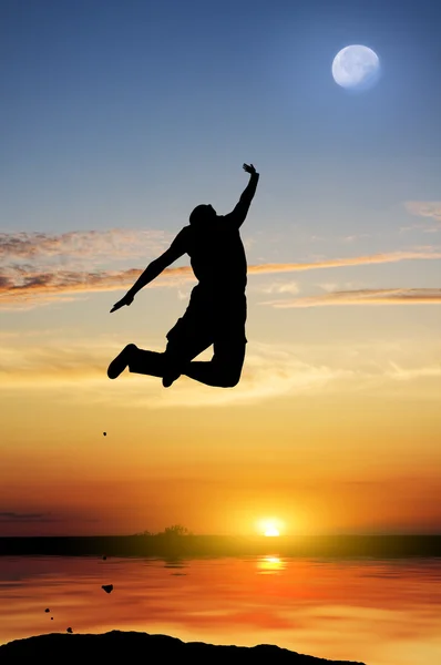 Силуэт человека, прыгающего на закате — стоковое фото