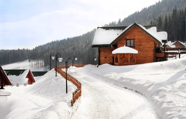 stock image Wooden house in mountains at a road in winter