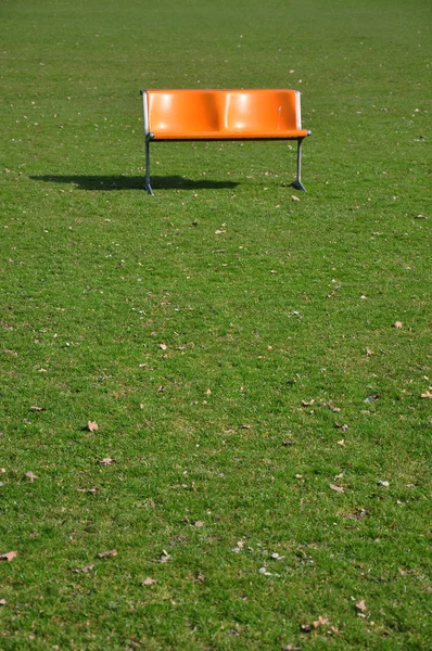 芝生の上のオレンジ色のベンチ — ストック写真