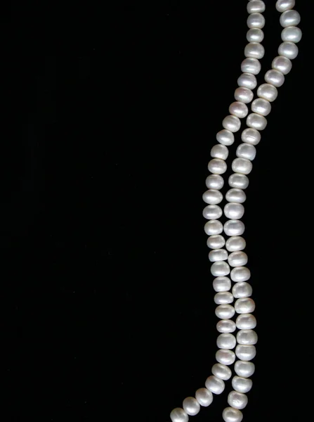 Białe perły na czarny jedwab jako tło — Zdjęcie stockowe