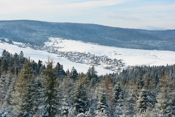 Χωριό στην κοιλάδα ανάμεσα σε βουνά του χειμώνα — Φωτογραφία Αρχείου