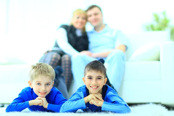 Smiling children looking for presents in Christmas boots and family on sofa — Stockfoto
