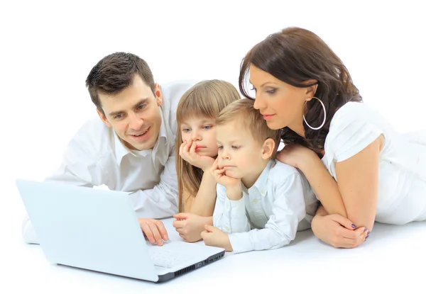 Liefdevolle familie op zoek naar een laptop liggen op bed thuis — Stockfoto