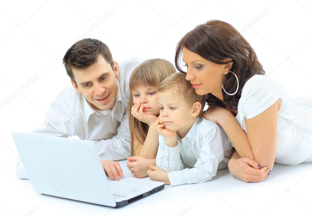 Loving family looking at a laptop lying down on bed at home