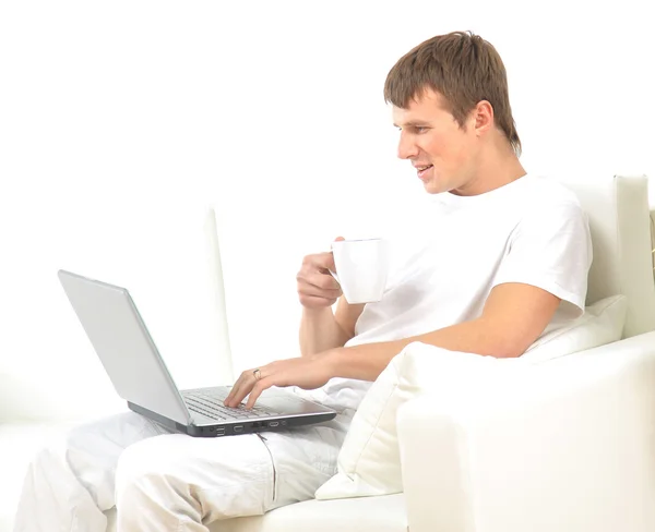 Muž sedí na pohovce a pracuje na jeho laptopu — Stock fotografie