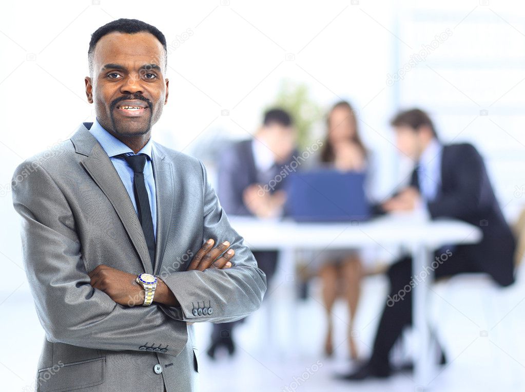 Happy african-american businessman with his team working behind