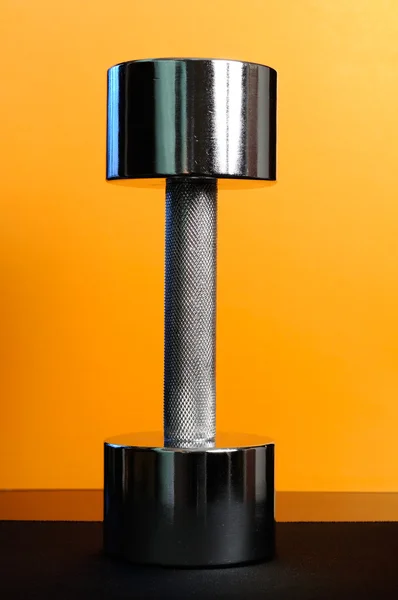 Металлический 10-фунтовый гантель на оранжевом фоне — стоковое фото
