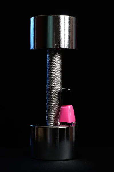 Mancuerna de metal con esmalte de uñas rosa sobre fondo negro — Foto de Stock