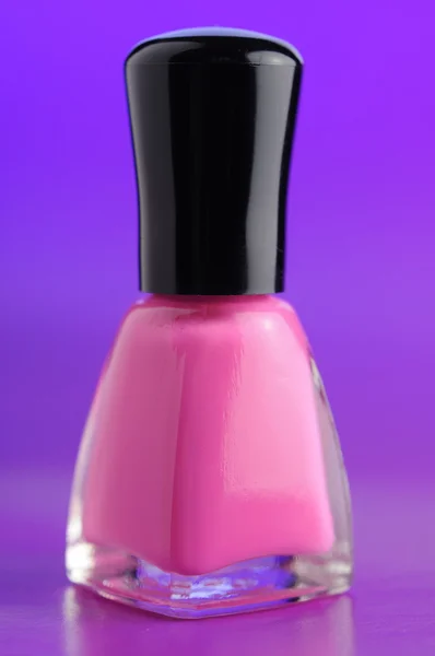 Esmalte de uñas rosa sobre fondo púrpura con estilo — Foto de Stock
