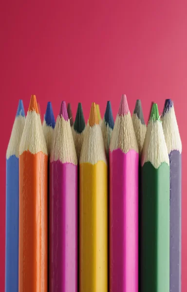 Kolorowe ołówki na czerwonym tle — Zdjęcie stockowe
