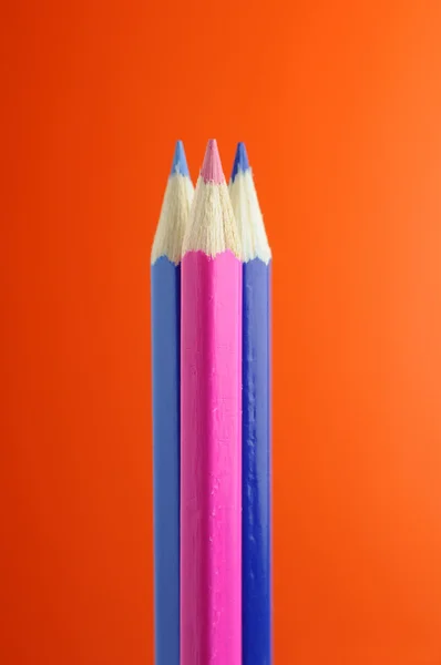 Blauwe en roze potloden op oranje achtergrond — Stockfoto