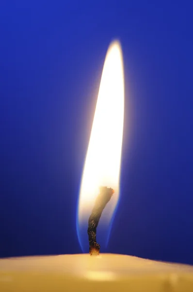 Hořící svíčka plamen close-up na modrém pozadí — Stock fotografie