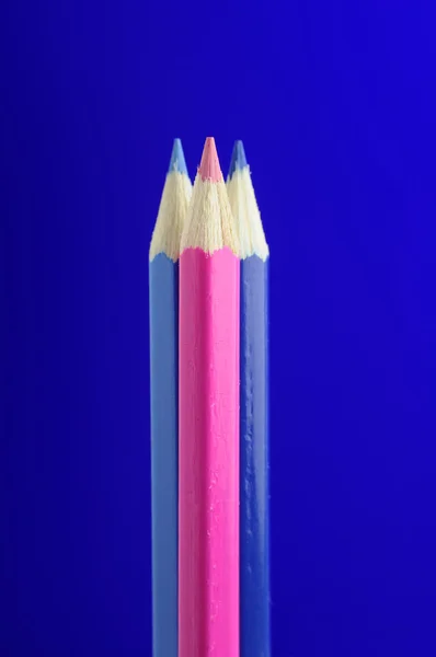 Lápices de color rosas y azules sobre fondo azul — Stockfoto