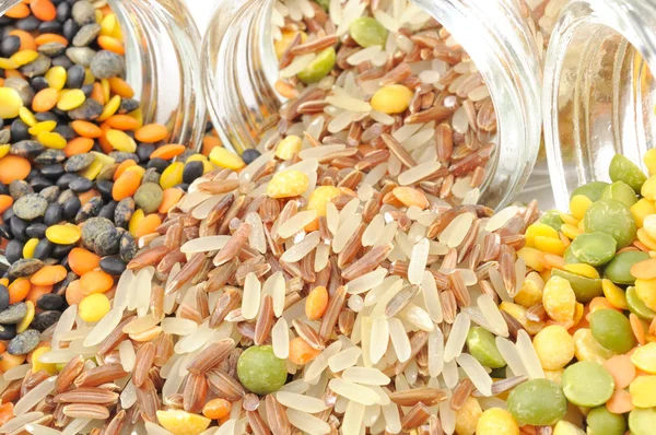 Cereali assortiti che fuoriescono dai barattoli di vetro — Foto Stock