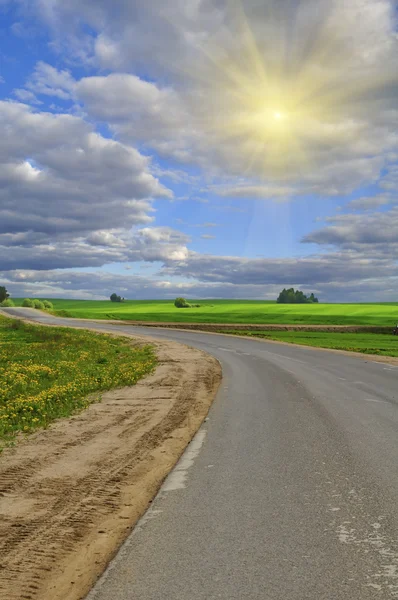 Pustej drodze i przedzierając się przez chmury słońce — Zdjęcie stockowe