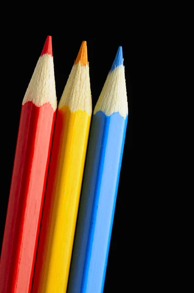 Fekete háttér piros, a sárga és a kék ceruzák — Stock Fotó