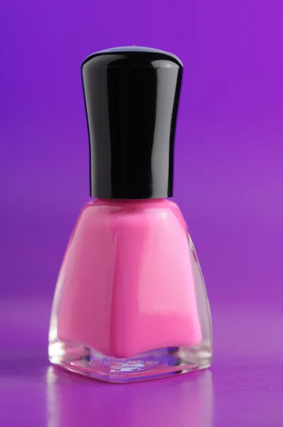 Esmalte de uñas rosa sobre fondo púrpura — Foto de Stock