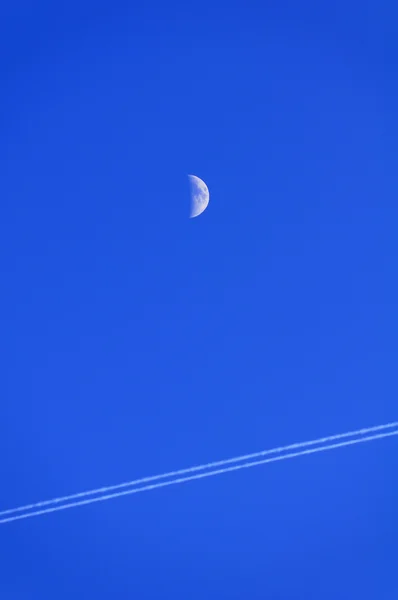 Maan en condensatie trail in blauwe hemel — Stockfoto
