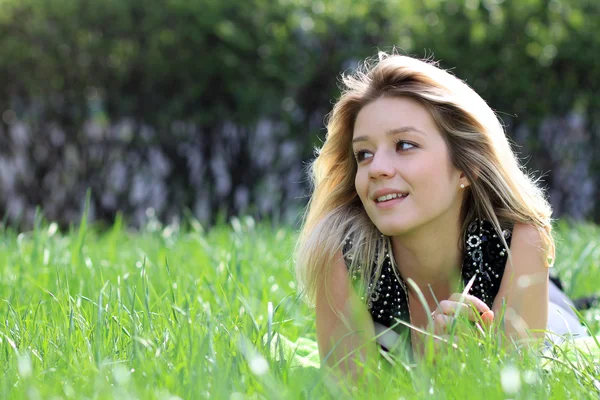 Блондинка лежит на травяном поле в парке — стоковое фото