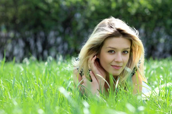Blonde liggend op grasveld in het park — Stockfoto