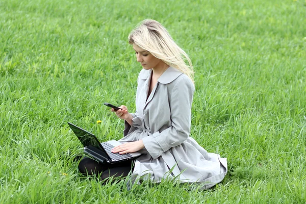 Mädchen arbeitet am Laptop und telefoniert — Stockfoto