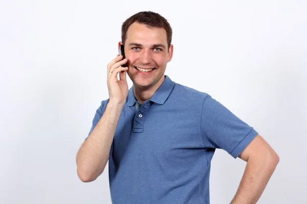 Usmívající se mladý muž na jeho mobilní telefon — Stock fotografie