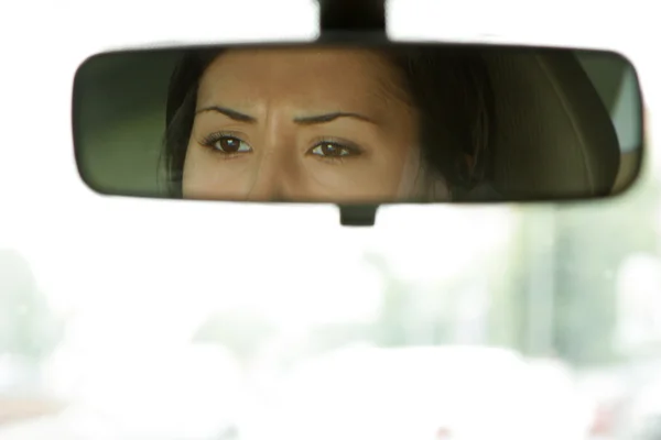 stock image Woman sits on driver's seat and Looks in the rear-view mirror